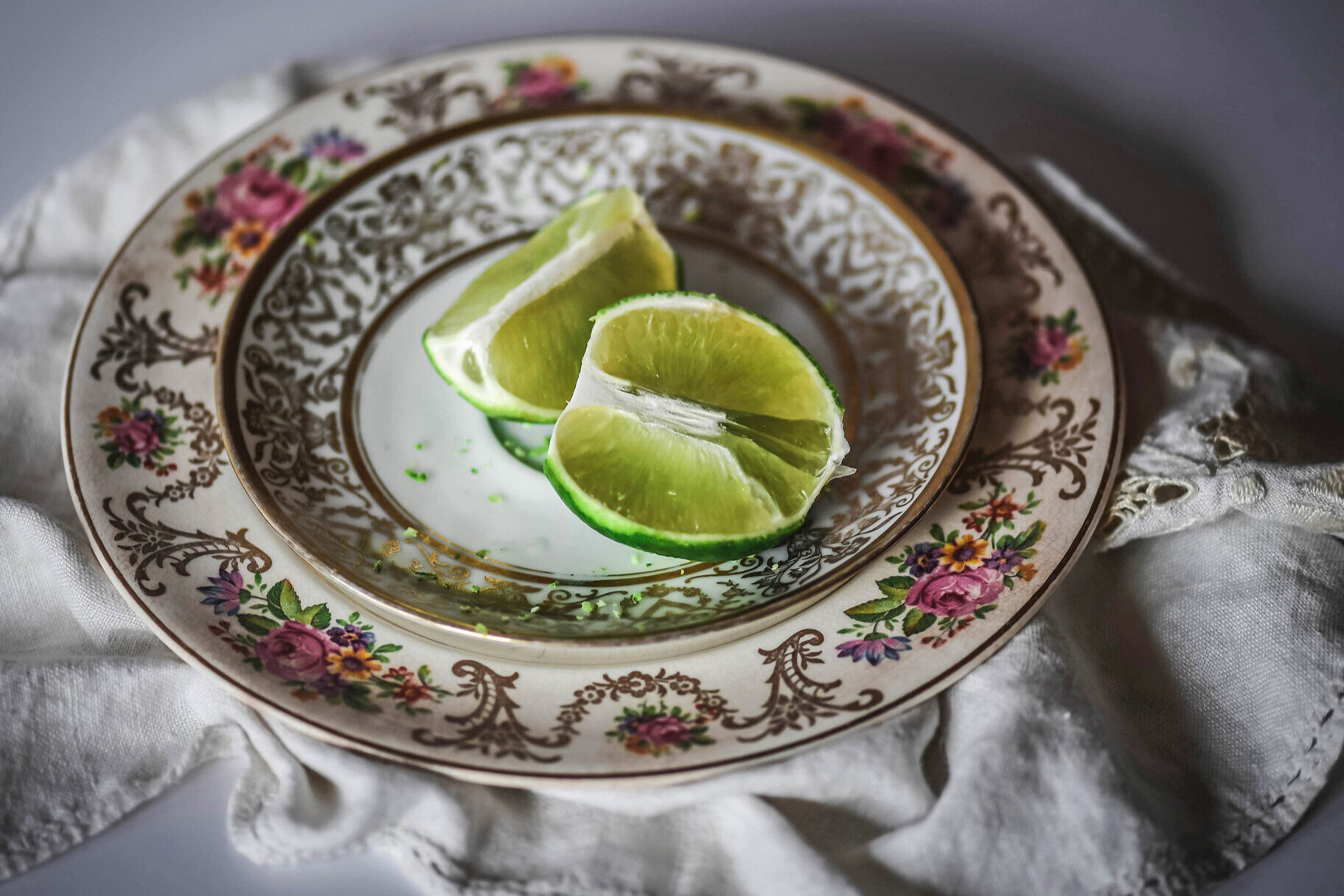 Still life of lime pieces on stacked decorative floral plates.