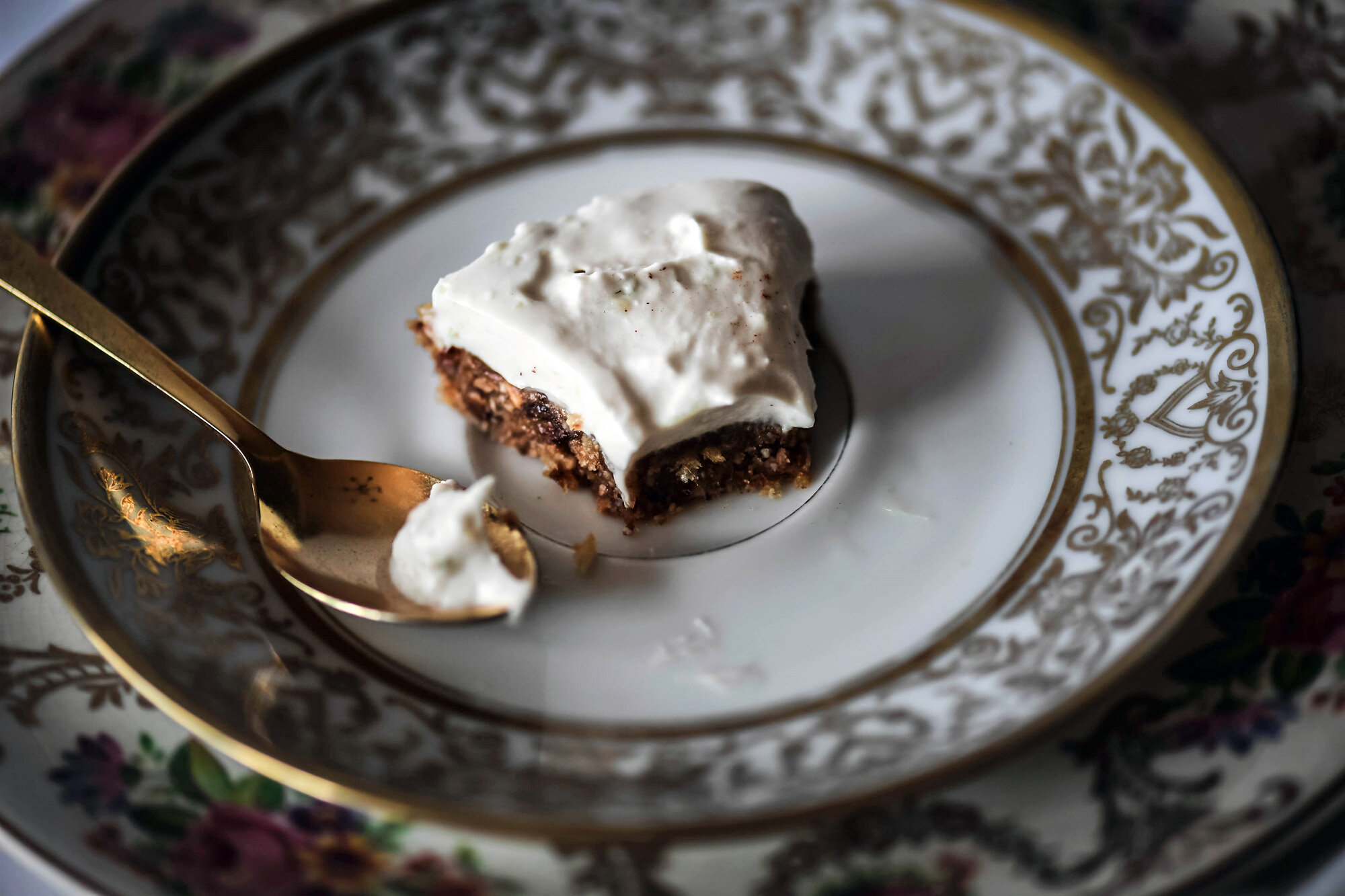 Spoonful of vegan and gluten-free no bake key lime pie with pie slice on decorative golden plates.