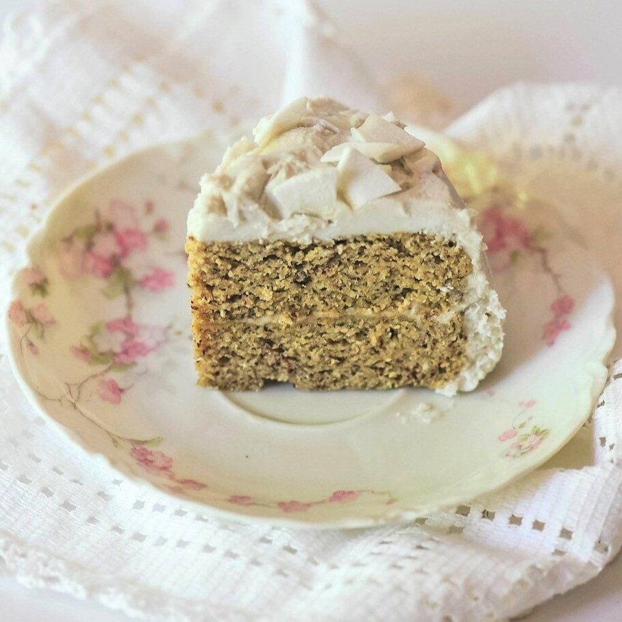 Slice of homemade mini gluten free coconut cake with almond flour topped with coconut flakes.